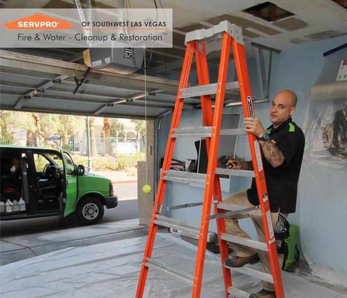 SERVPRO Tech on a ladder restoring a water damaged ceiling in a garage in Las Vegas, NV.