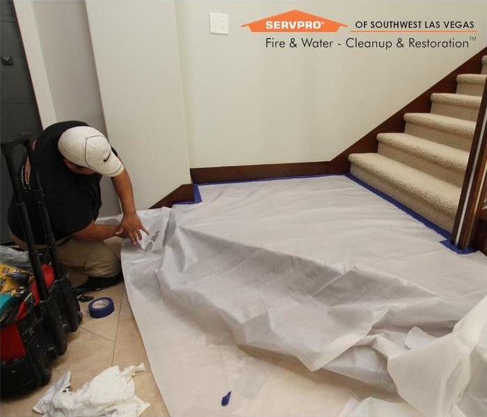 Water damage restoration technician covering a staircase.